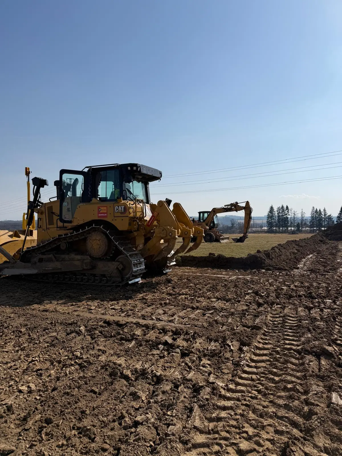 Pásový dozer CAT D6 s rozrývačem při skrývce ornice