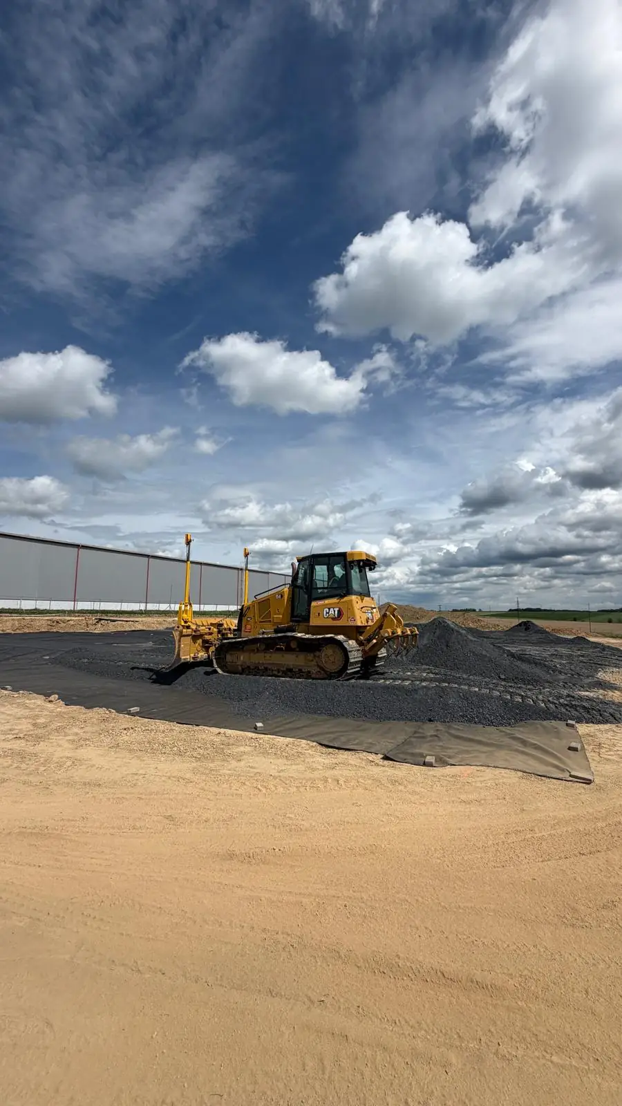 Dozer CAT D4 s GPS nivelací rozhrnuje drcené kamenivo na geotextilii