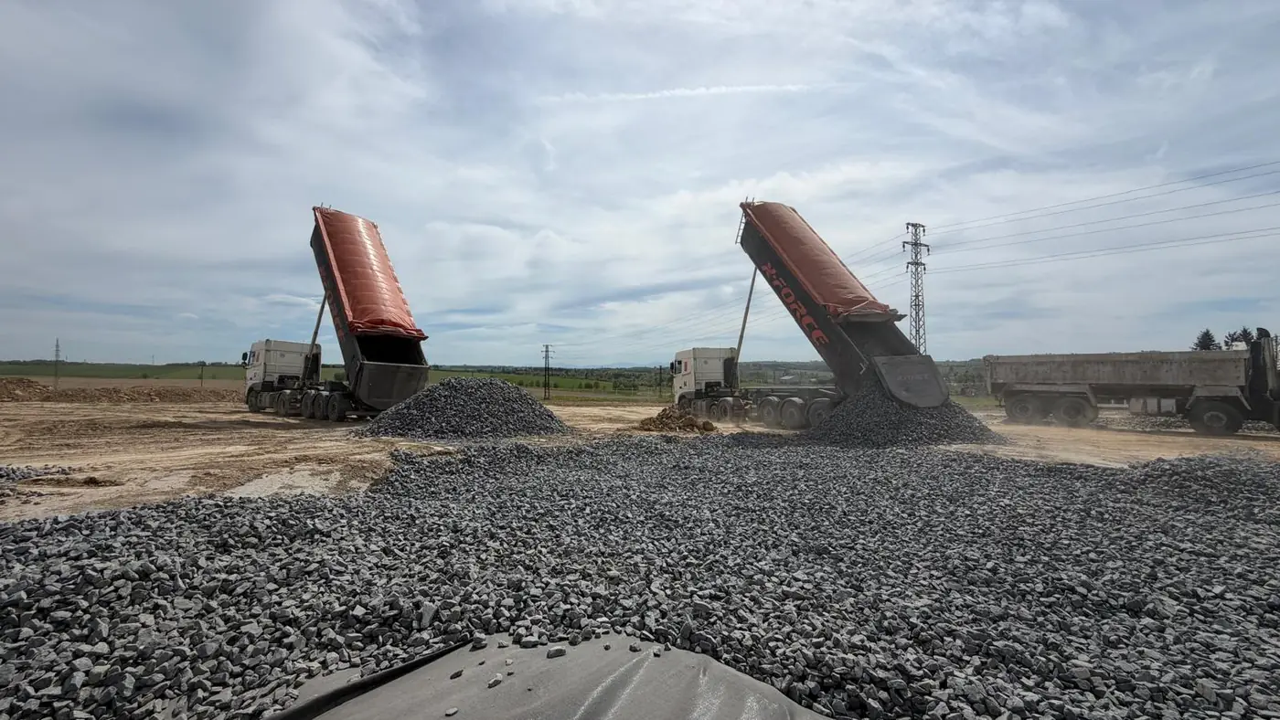 Nákladní souprava vysypává drcené kamenivo na sanovanou pláň